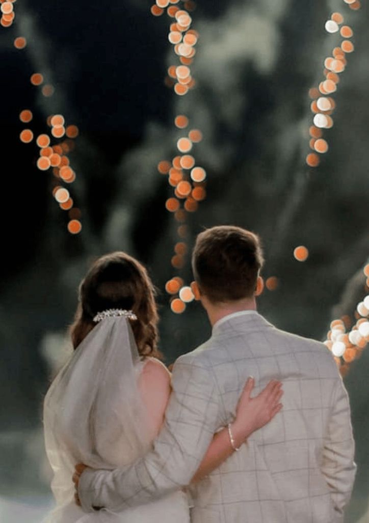Bride and groom with arms around each other watching the fireworks