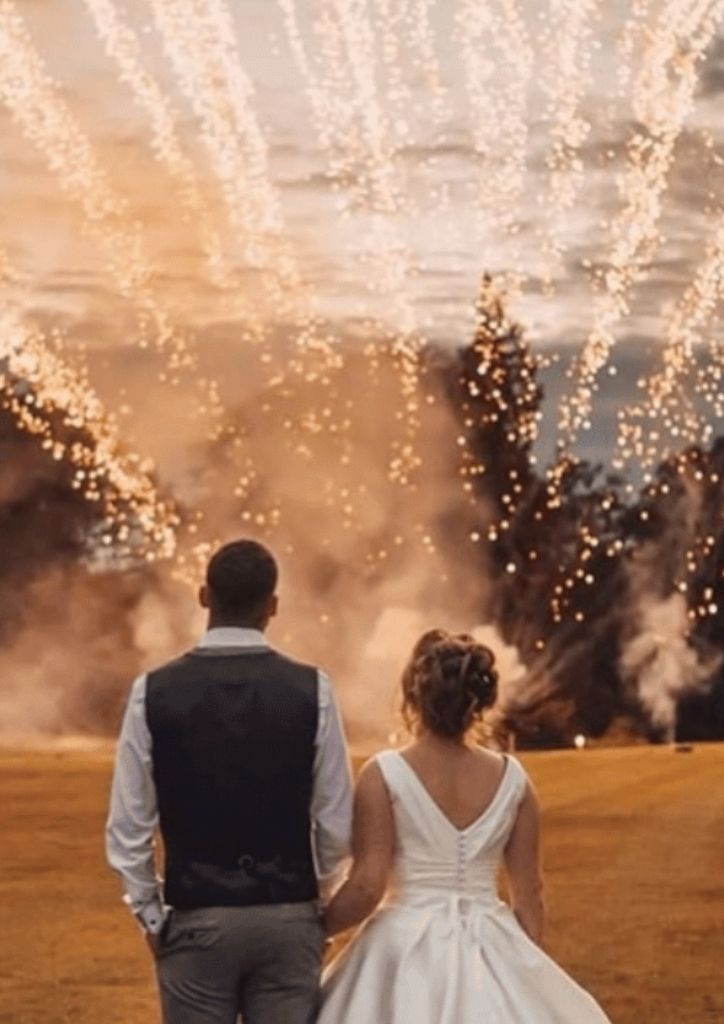 Newly-wed couple holding hands watching fireworks in the distance 