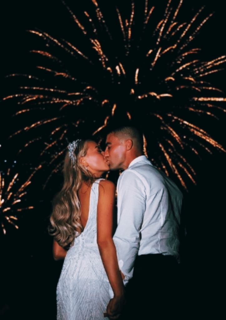 Newly-wed couple kissing with fireworks in the background